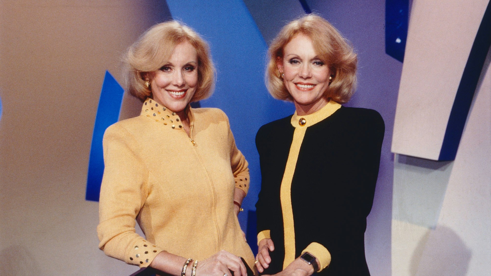 Die Kessler-Zwillinge stehen in einer TV-Kulisse.