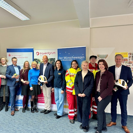 Männer und Frauen stehen nebeneinander vor Bannern.