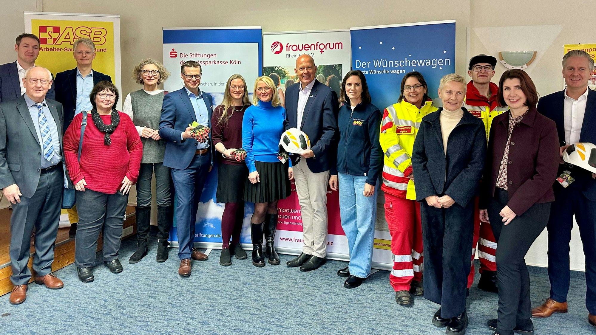 Männer und Frauen stehen nebeneinander vor Bannern.