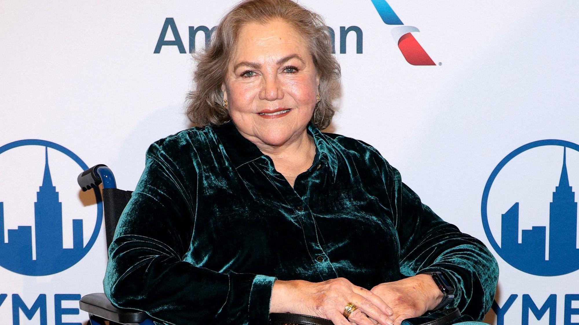 Kathleen Turner sitzt in einem Rollstuhl.