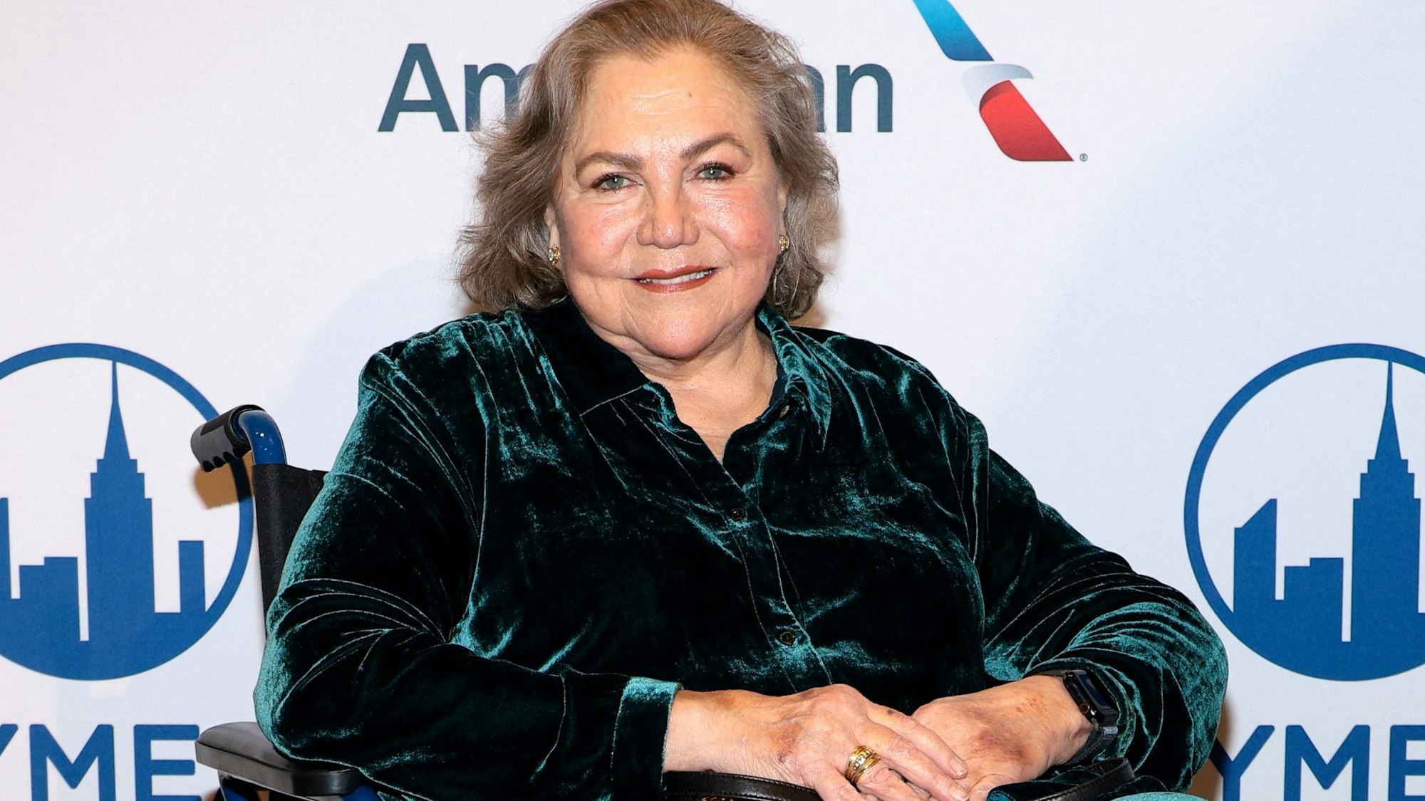 Kathleen Turner sitzt in einem Rollstuhl.