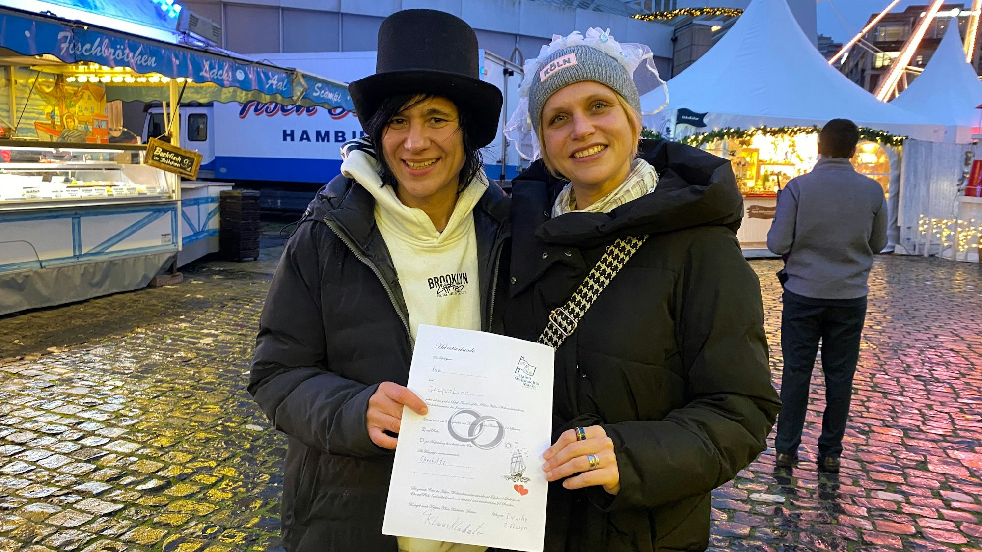 Zwei Frauen halten sich im Arm und halten eine Urkunde in die Kamera.