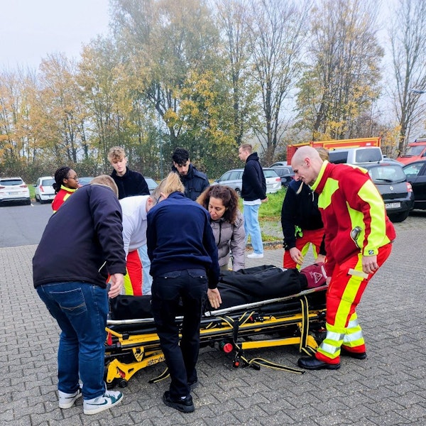 Das Foto zeigt Menschen, die einen Dummy auf einer Liege transportieren.
