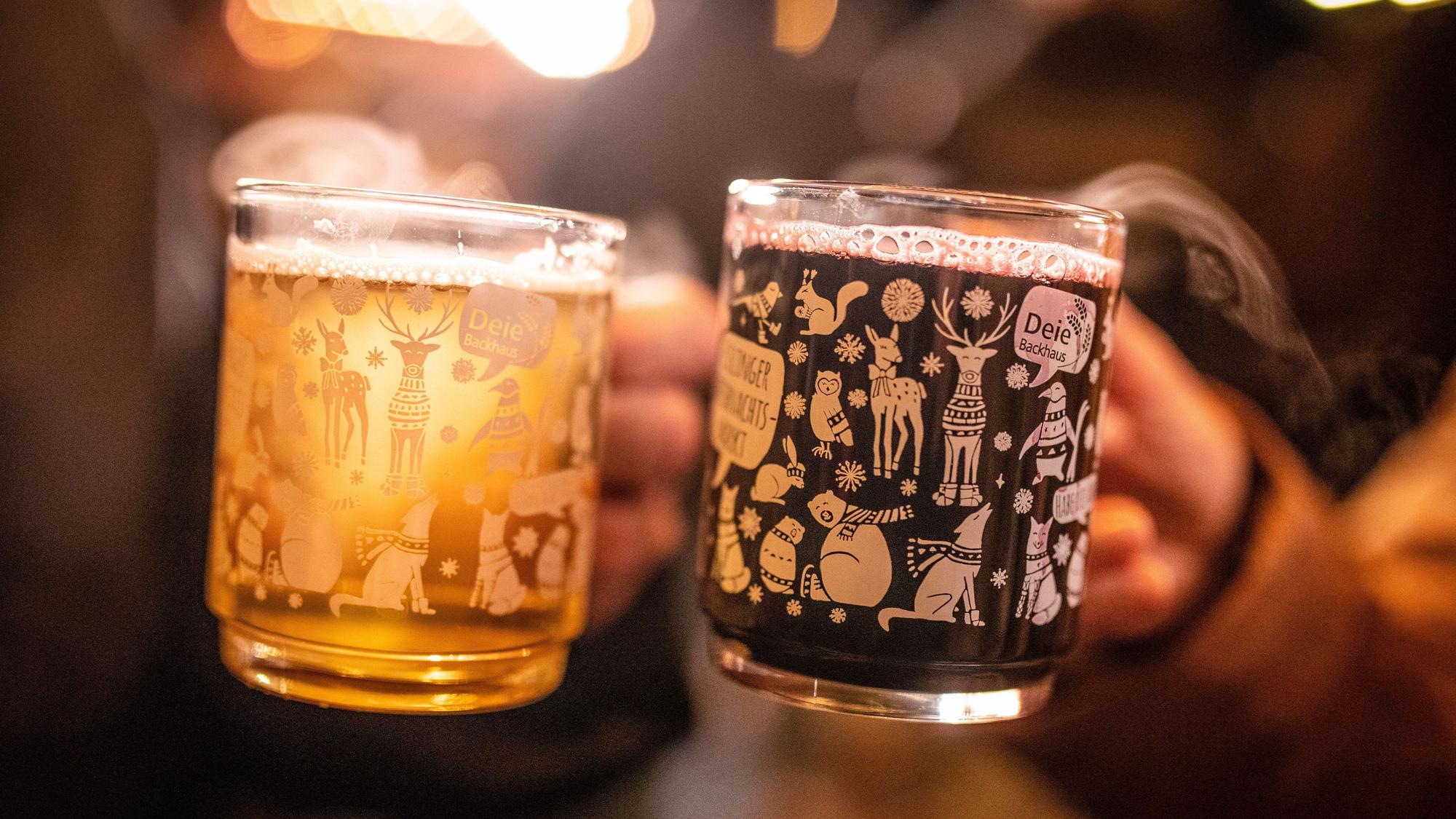 Zwei Frauen stoßen mit einem roten und einem weißen Glühwein an