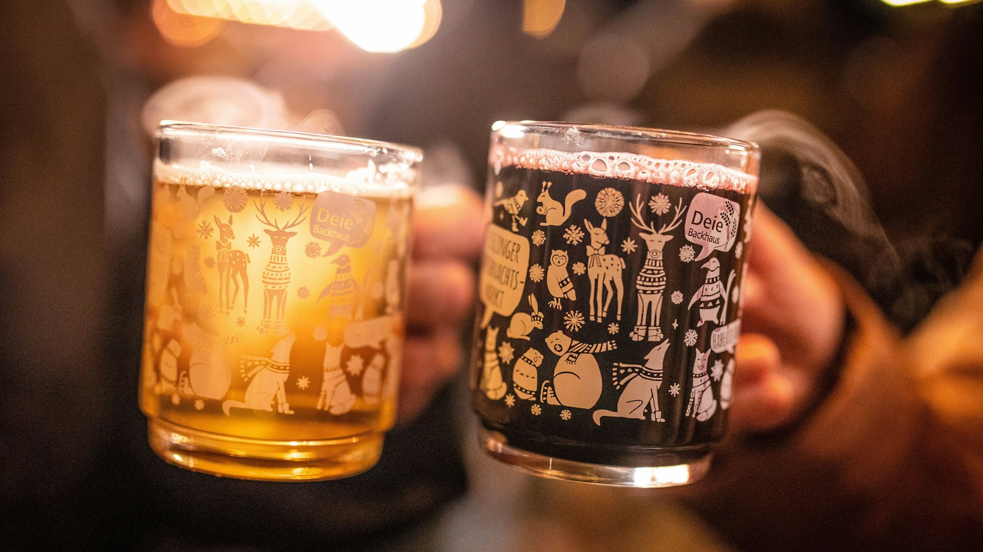 Zwei Frauen stoßen mit einem roten und einem weißen Glühwein an