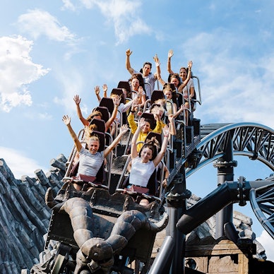 Zu sehen ist eine vollbesetzte Achterbahn.