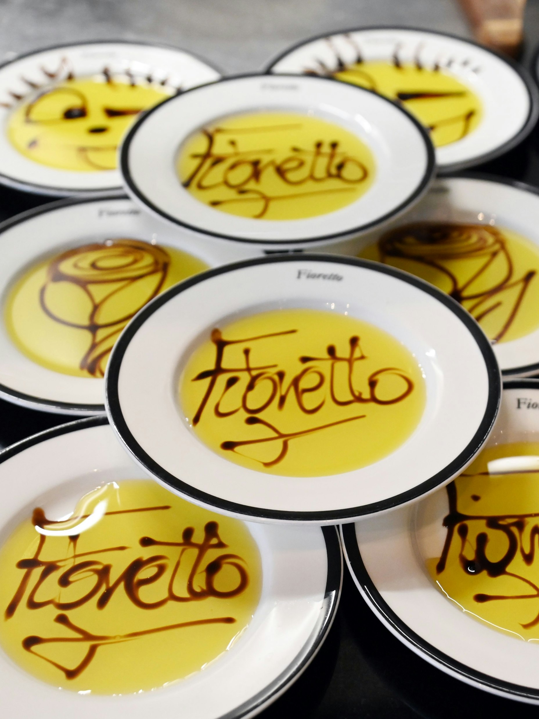 Teller mit Öl sind zu sehen, in denen der Schriftzug Fioretto mit Essig gezogen wurde.
