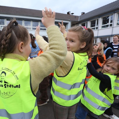 Zu sehen sind Kinder, die Warnwesten tragen.