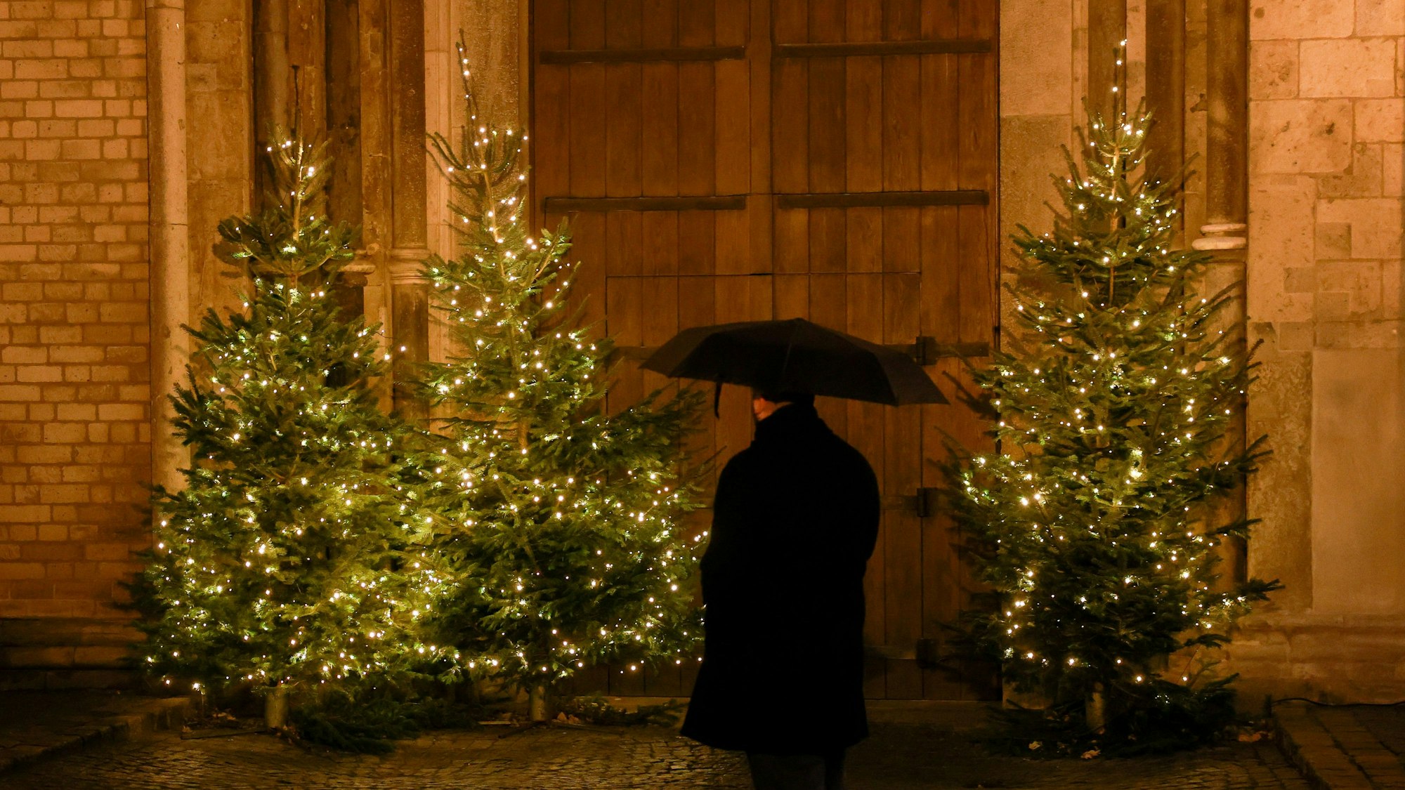 Das Bild zeigt einen alleine vor Weihnachtsbäumen stehenden Mann. (Symbolbild)