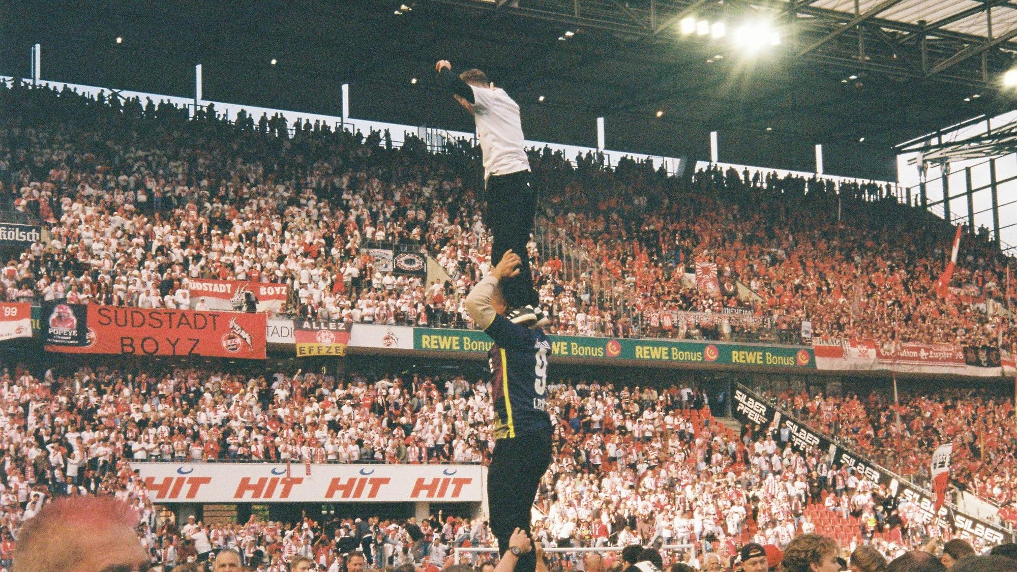 Der 1. FC Köln steigt wieder auf: Szene der Freude spielen sich im Rhein-Energie-Stadion ab. Hier sieht man einen Menschenturm: Einer hält zwei Personen, oben steht ein Kind.