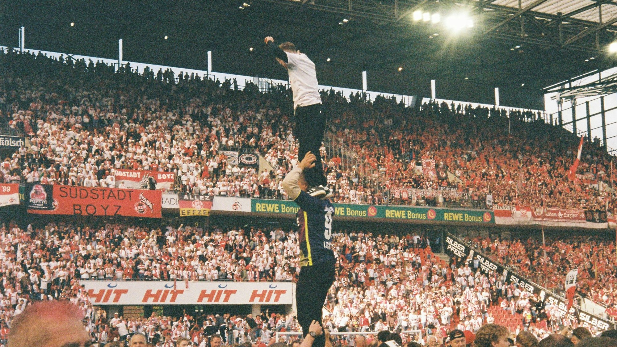 Der 1. FC Köln steigt wieder auf: Szene der Freude spielen sich im Rhein-Energie-Stadion ab. Hier sieht man einen Menschenturm: Einer hält zwei Personen, oben steht ein Kind.