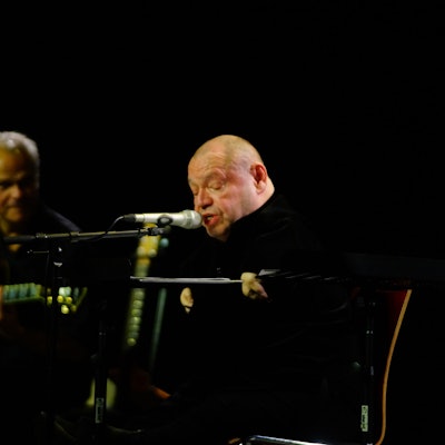 Auf dem Bild sind zwei Musiker auf einer Bühne zu sehen.