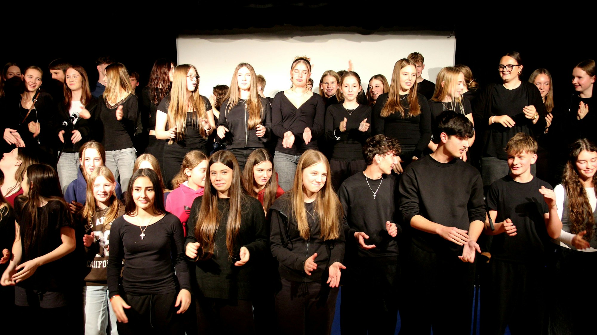 Auf dem Bild ist eine große Gruppe von Schülern auf einer Bühne zu sehen.