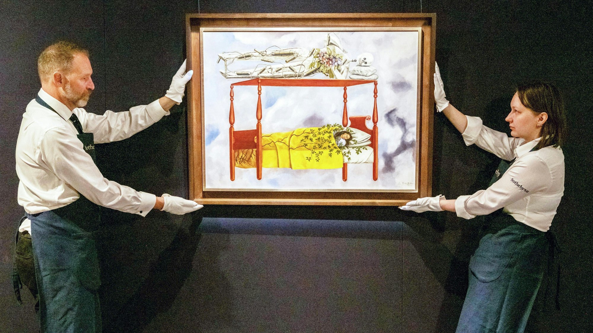 Das Selbstporträt "El sueño (La cama)", übersetzt: Der Traum (Das Bett), der mexikanischen Künstlerin Frida Kahlo wird von zwei Mitarbeitern von Sotheby's gehalten.