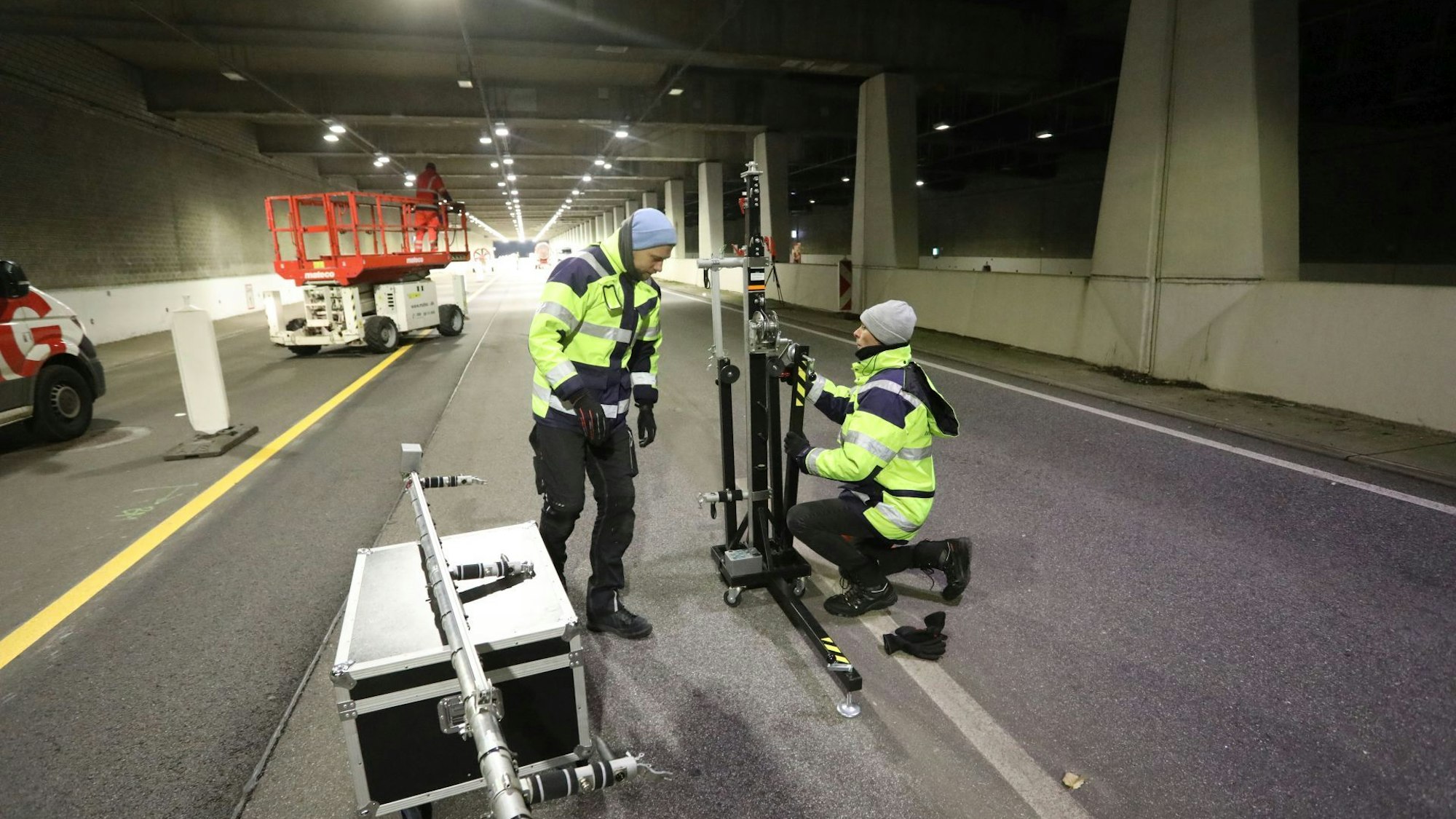 Zwei Männer an einem Metallgestell, das sie gerade zusammensetzen. Im Hintergrund eine Scherenbühne.