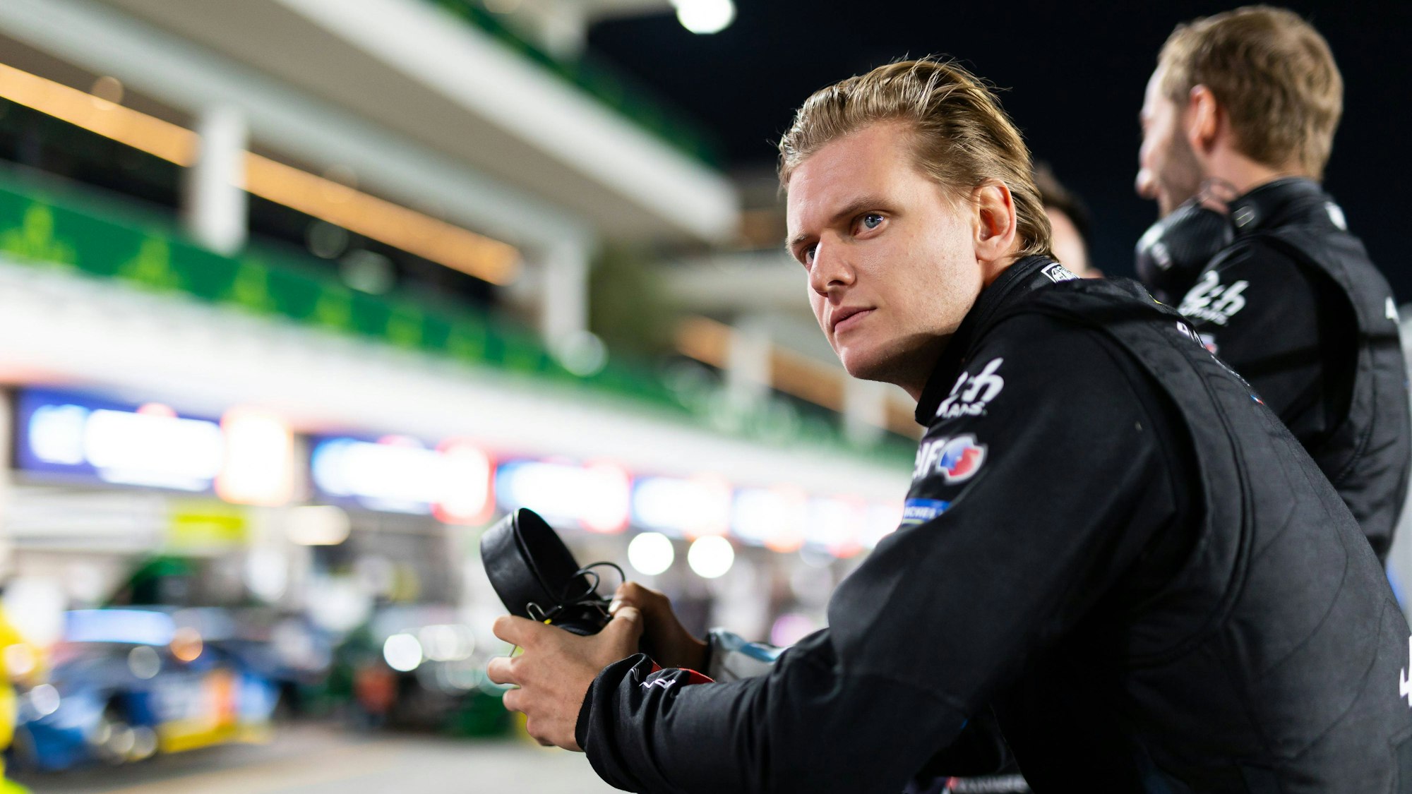 Mick Schumacher steht an der Boxenmauer.