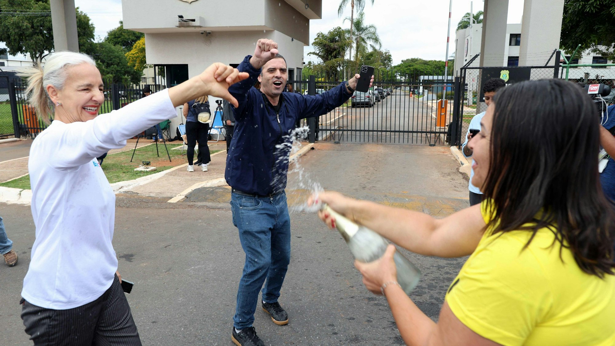 Vor der Bundespolizeizentrale in Brasília stoßen Demonstrierende auf die Festnahme von Jair Bolsonaro an, während sich auf der gegenüberliegenden Straßenseite seine Anhänger versammeln. Der frühere Präsident war am Morgen aus dem Hausarrest in Polizeigewahrsam überstellt worden.