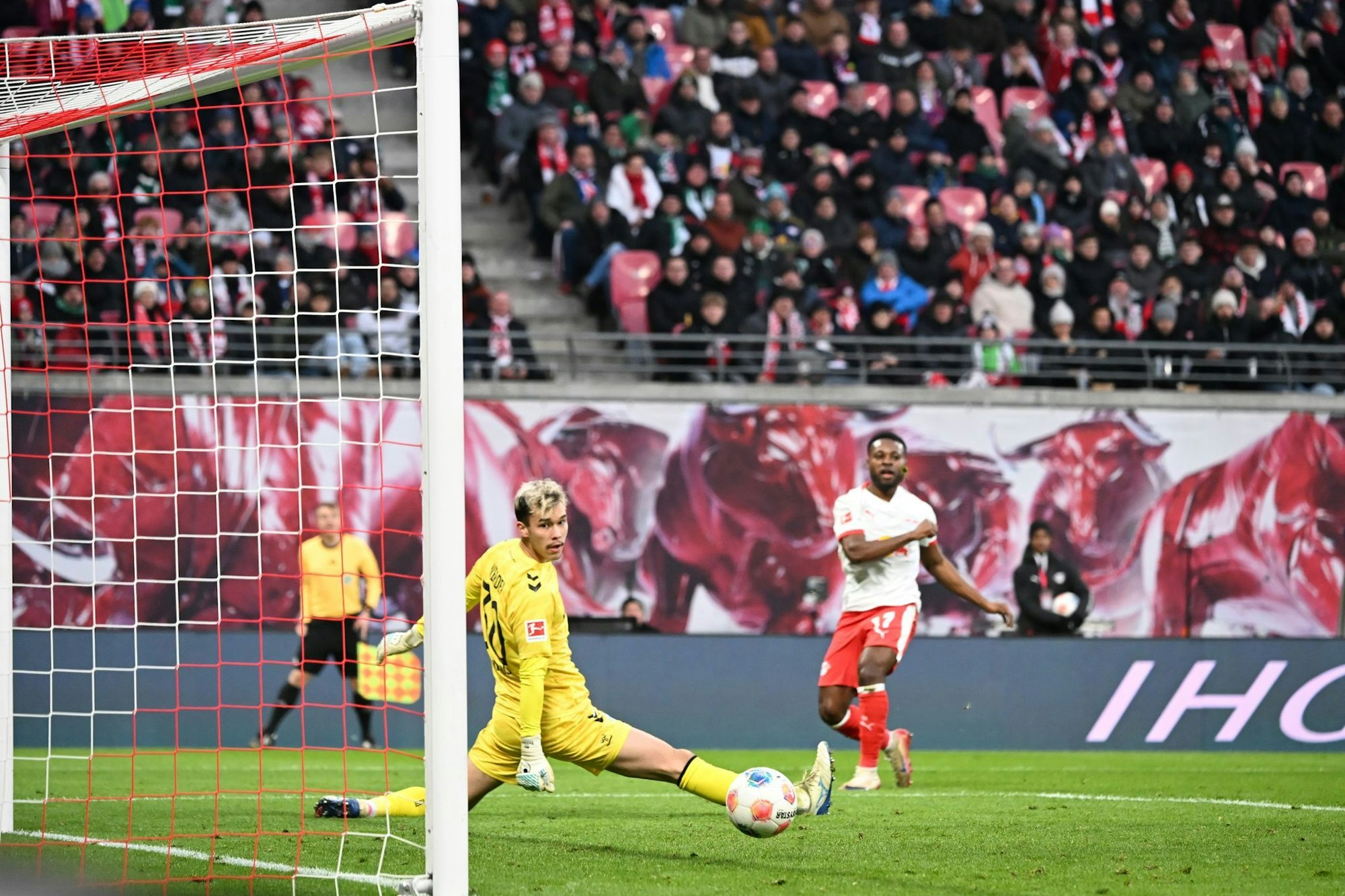 Bremens Torwart Mio Backhaus (l, Werder Bremen) und Ridle Baku (RB Leipzig) schauen dem Ball hinterher. Backhaus verhinderte mit seinen Paraden einen frühen Rückstand der Gäste in Leipzig.