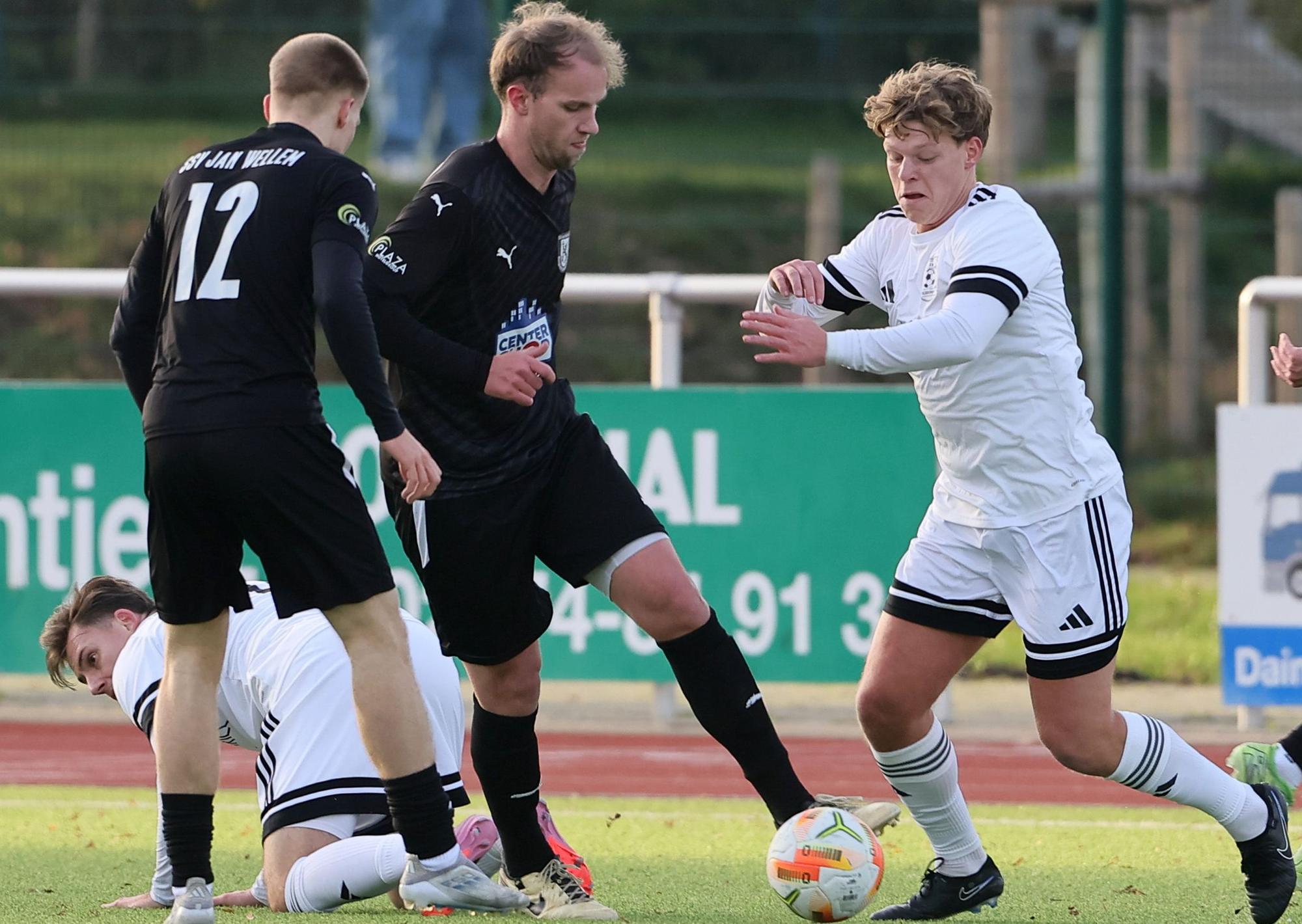 Das Foto zeigt Elsdorfs Niklas Kühnapfel (r.), der sich mit Ball der Übermacht zweier Wellemer Gegenspieler stellt.