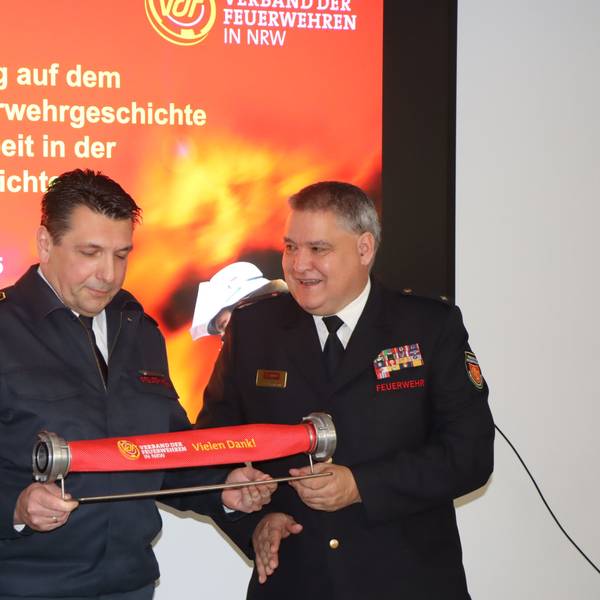 Das Foto zeigt Feuerwehrmänner, die einen kurzen Schlauch in der Hand halten.