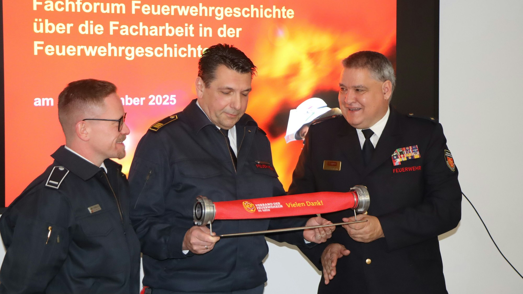 Das Foto zeigt Feuerwehrmänner, die einen kurzen Schlauch in der Hand halten.