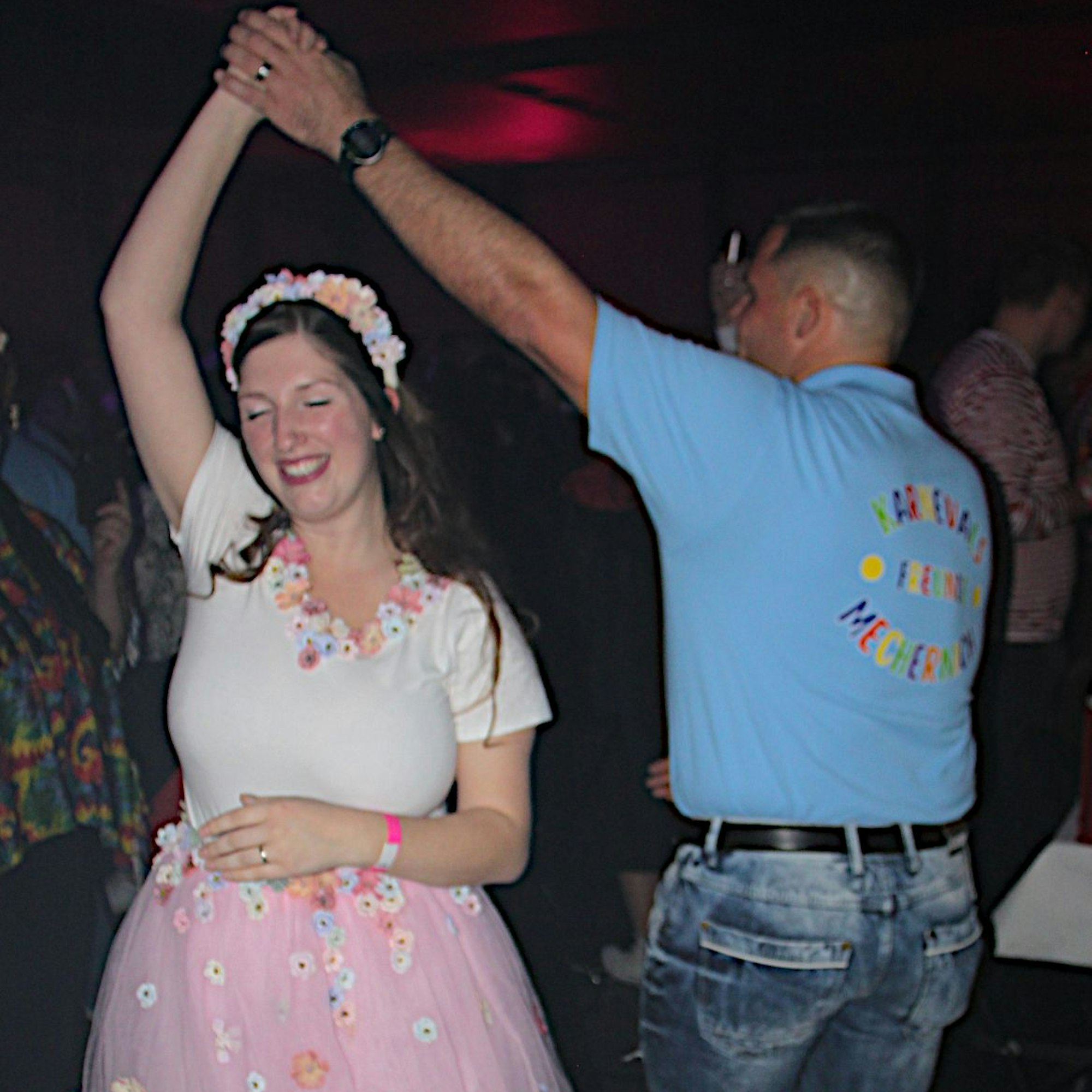 Das Paar tanzt zusammen. Die Frau hat einem Reifen mit Blumen im Haar.