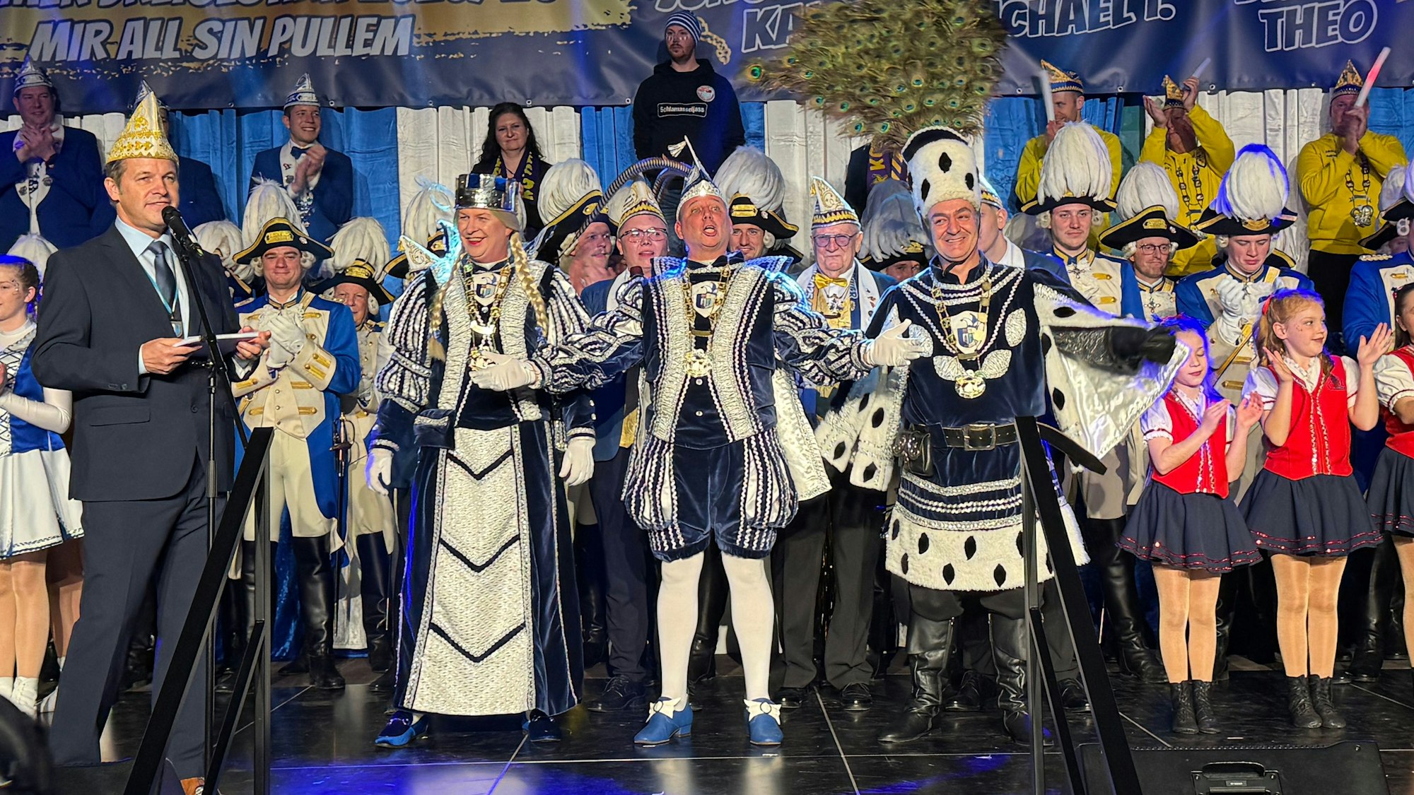 Das Fotos zeigt Menschen in Karnevalszunft, die auf einer Bühne stehen.