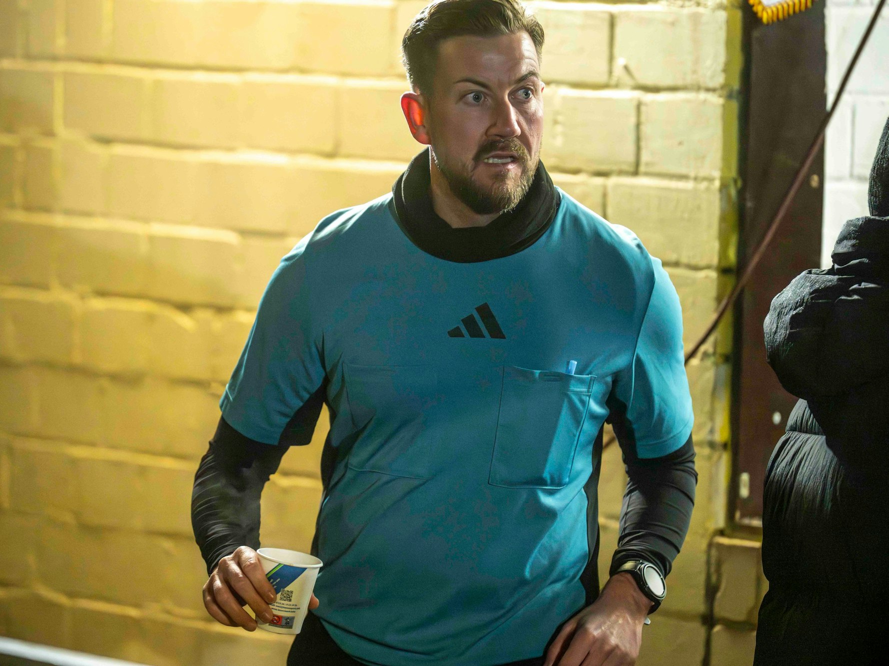 Schiedsrichter-Assistent Ron Fuß hält in der Halbzeitpause ein Heißgetränk in der Hand.