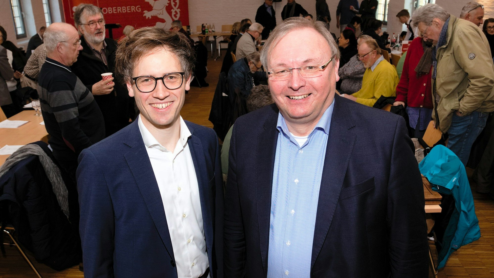 Zwei Männer stehen im Anzug nebeneinander.