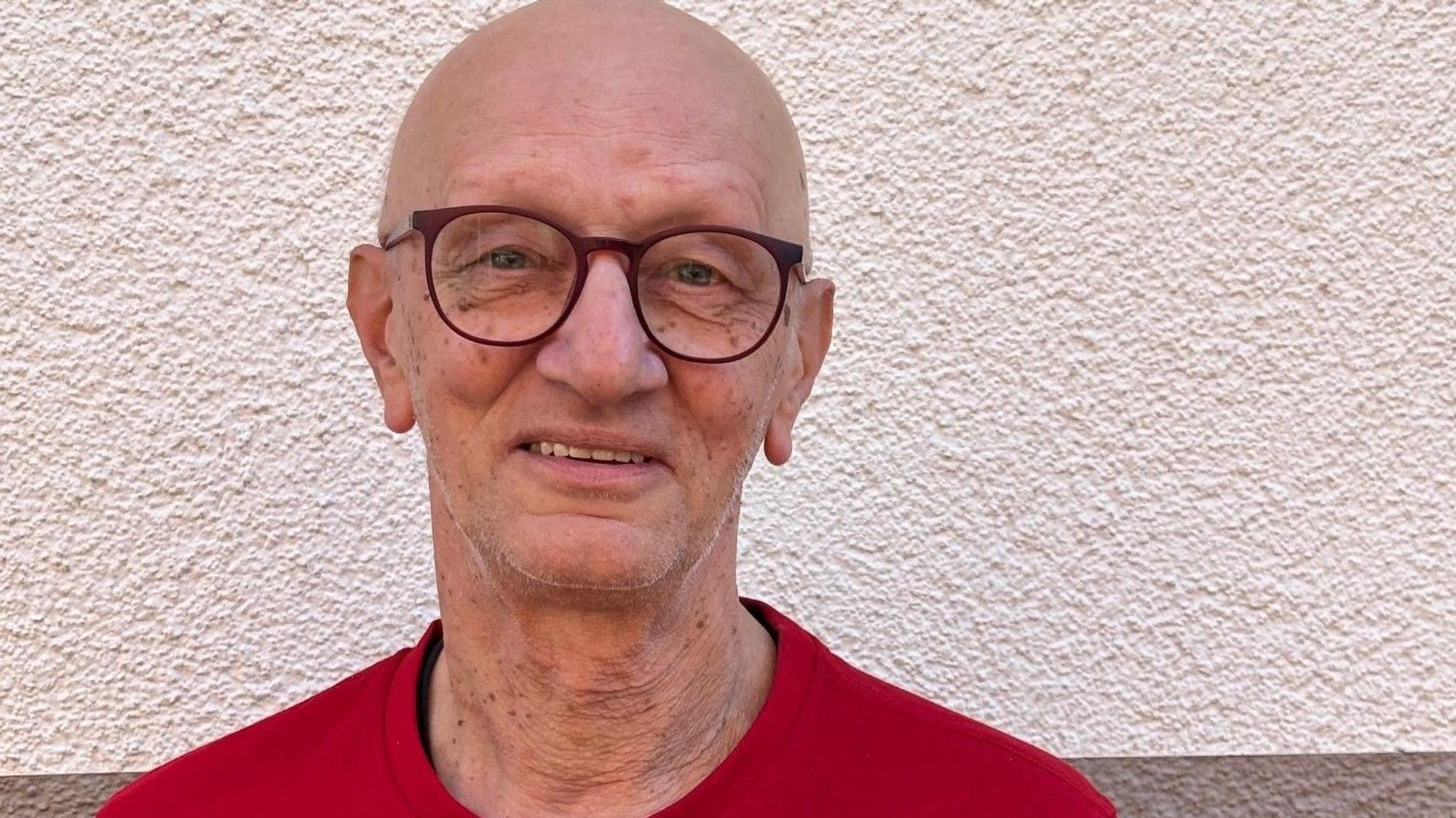Auf dem Bild ist das Portrait eines Mannes im roten T-Shirt zu sehen.