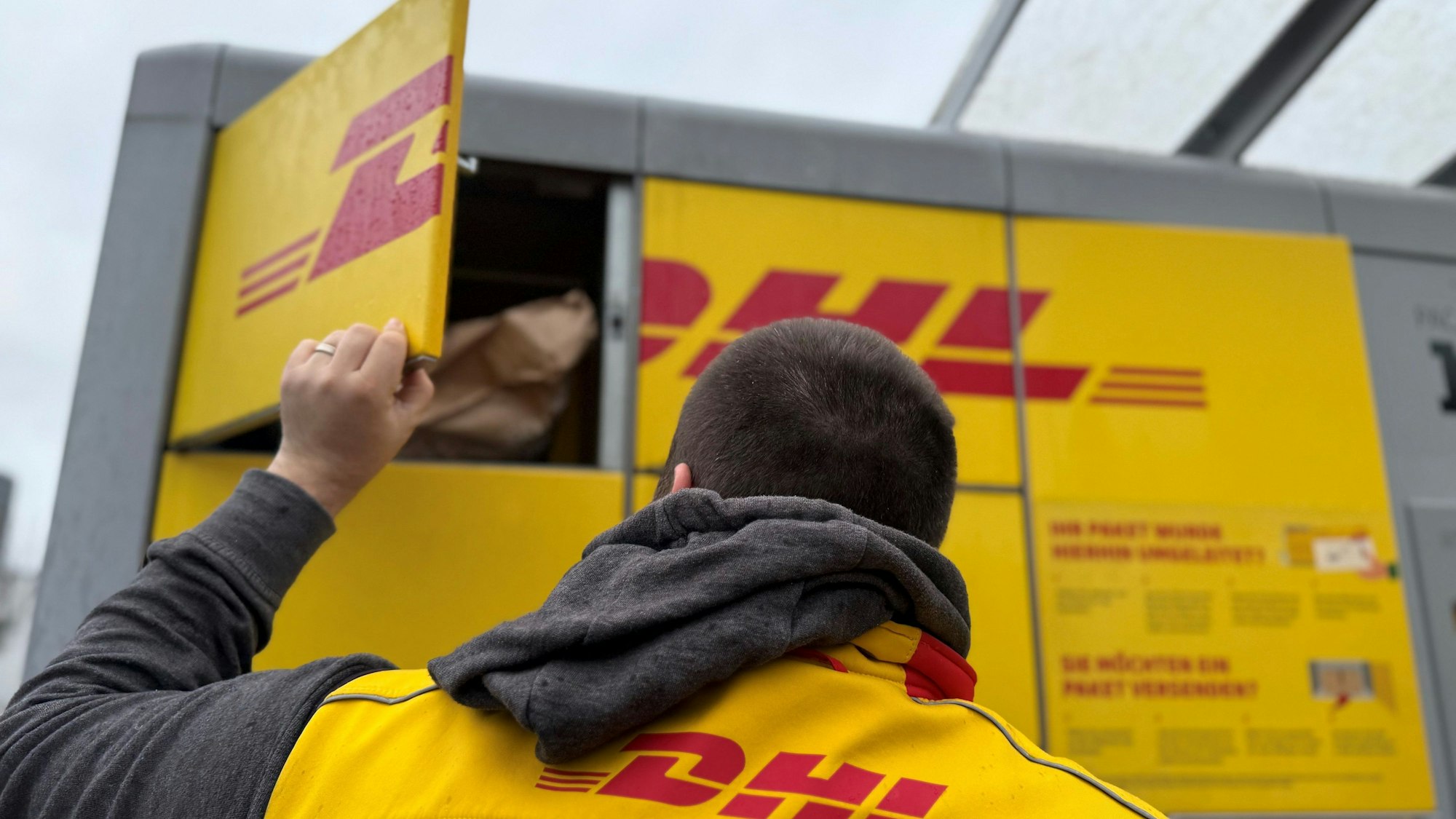 Ein Paketbote von DHL steht an einer Packstation, um diese mit Paketen zu befüllen. Schon im November ist die Paketmenge in Deutschland wegen der Black-Friday-Rabattaktionen und wegen des beginnenden Weihnachtsgeschäfts besonders hoch.