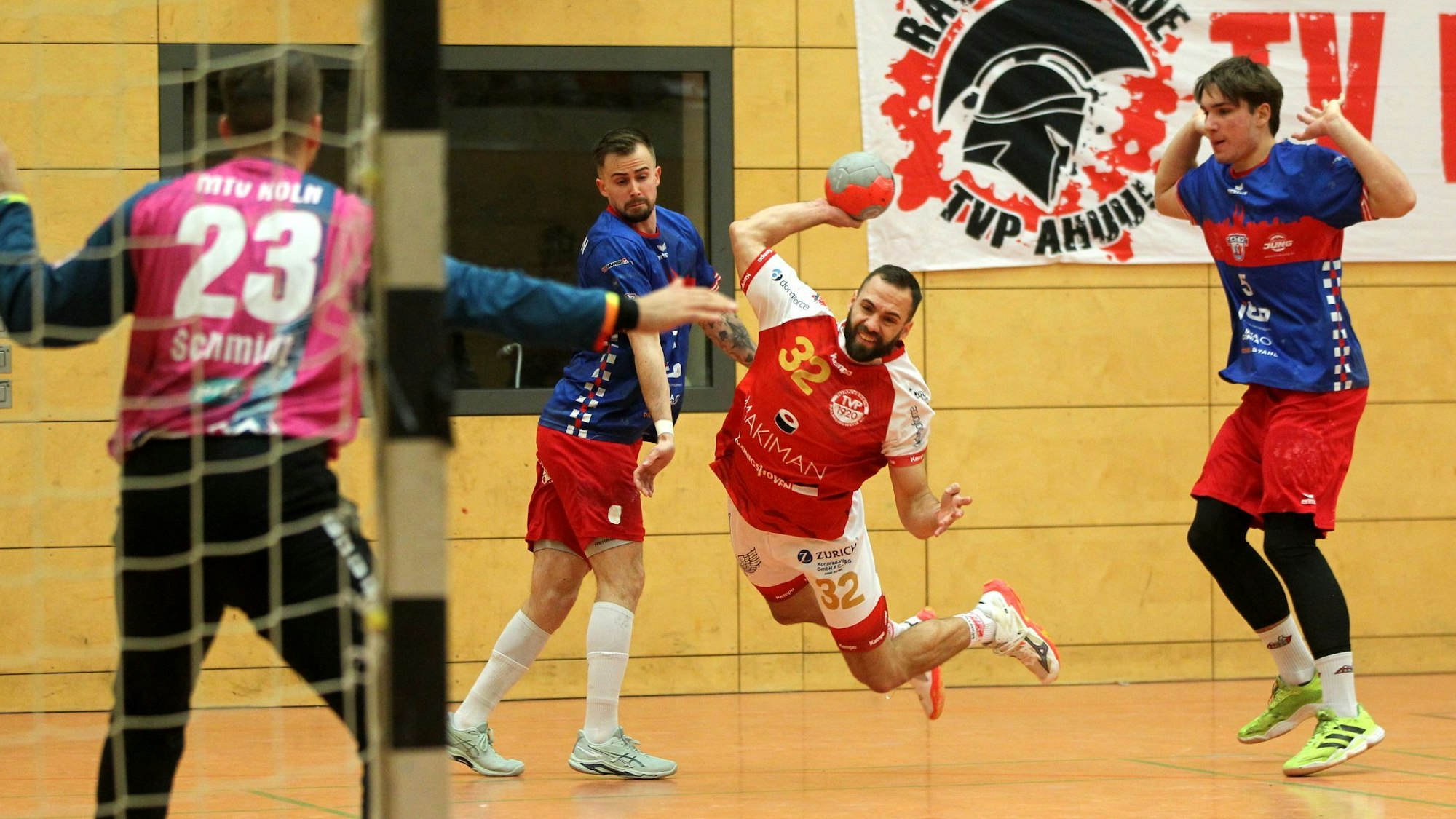 Dennis Schüller fliegt beim Wurf aufs Tor und ist von den Verteidigern nicht aufzuhalten.