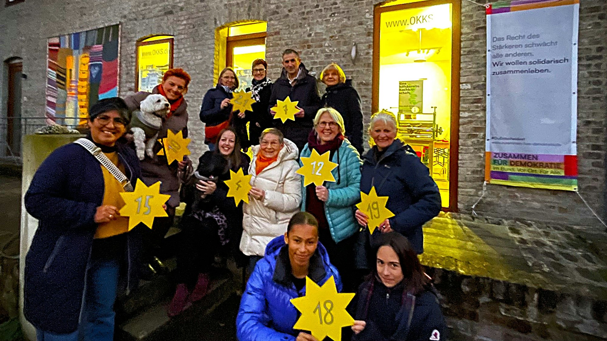 Mehrere Menschen halten einen gelben Stern mit einer Zahl darauf in der Hand.