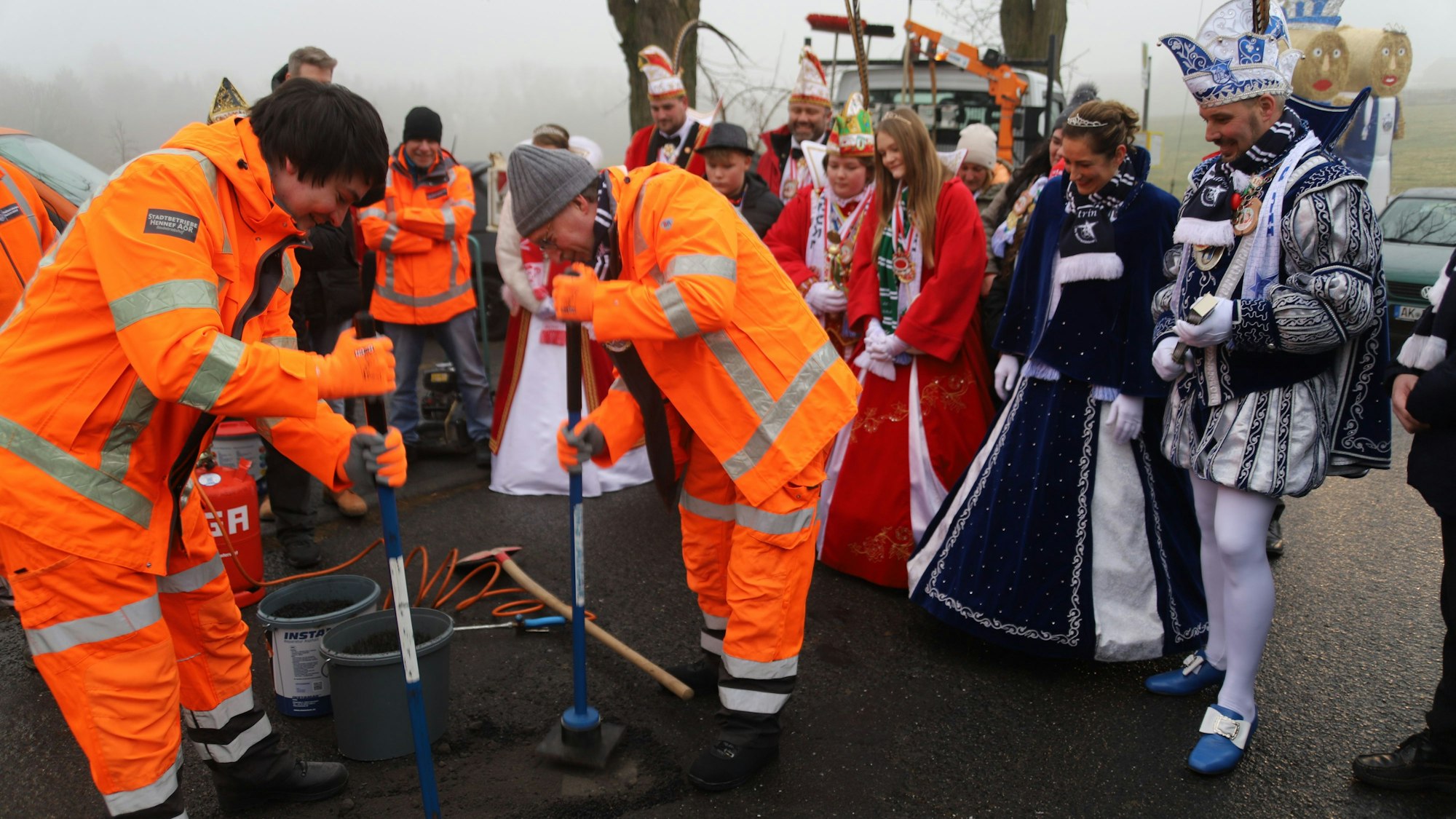Bürgermeister Mario Dahm und Vizebürgermeister Thomas Wallau (M., mit grauer Mütze) flickten in Uckerath die Ackerstraße, unter den gestrengen Augen des Prinzenpaars.