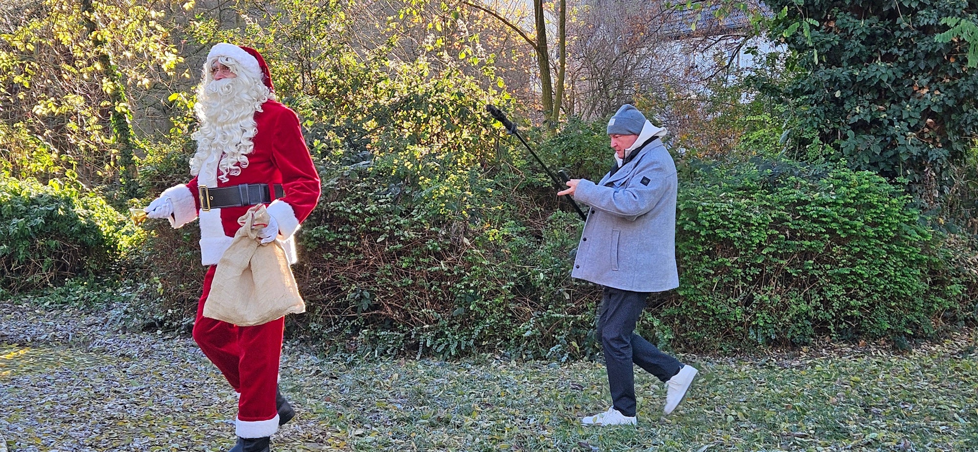 Ein Mann filmt einen anderen Mann im Weihnachtsmann-Kostüm.