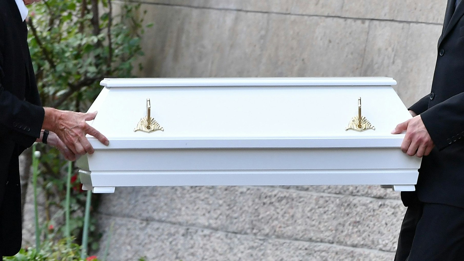 Am Ort des Familiendramas tragen Bestatter in Altenfeld (Thüringen) einen weißen Sarg für ein Kind aus dem Haus.