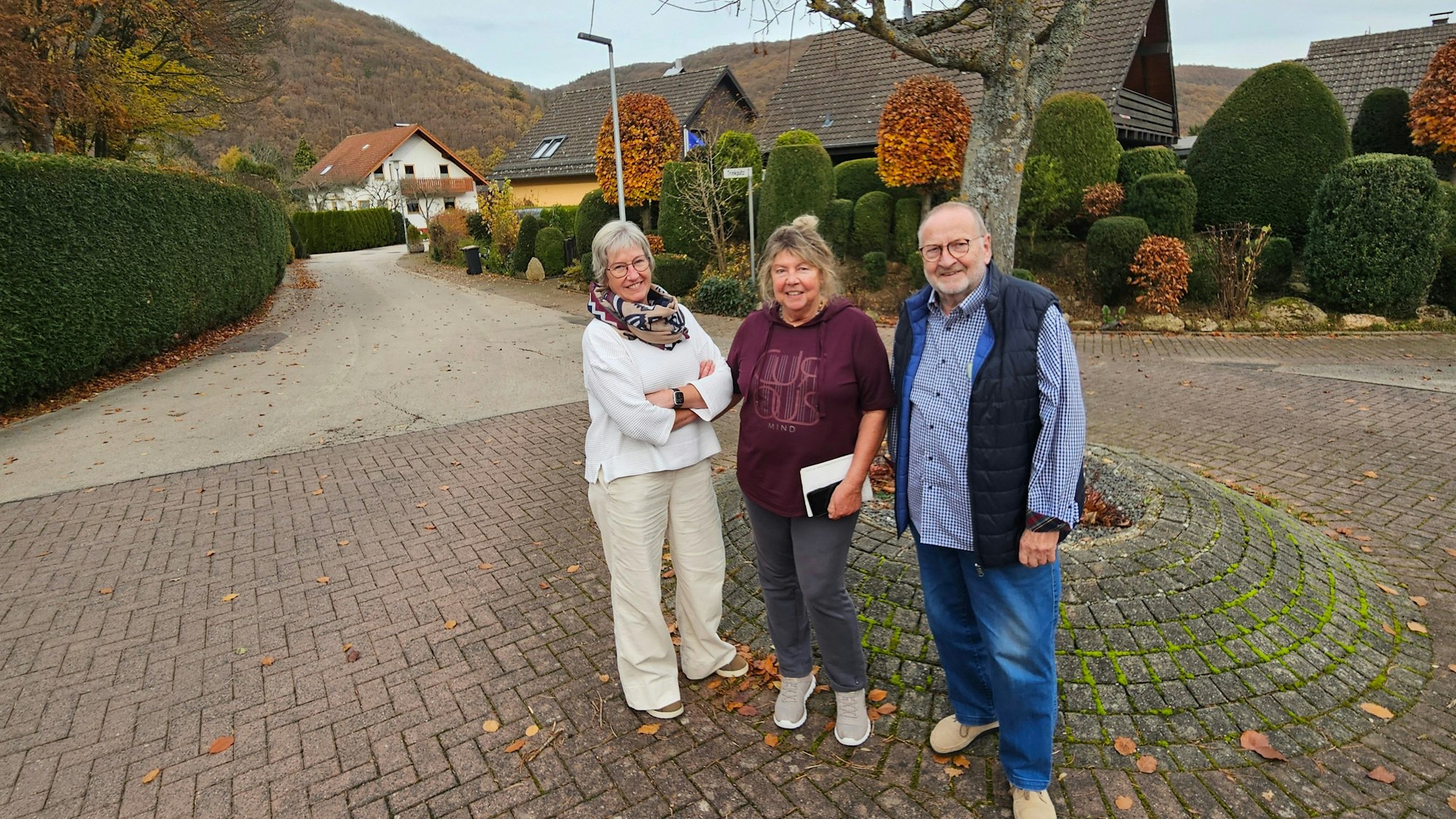 Irmie Poschen, Anne Kirch und Rainer Schmidt stehen nebeneinander an der Einfahrt zu ihrer Straße.