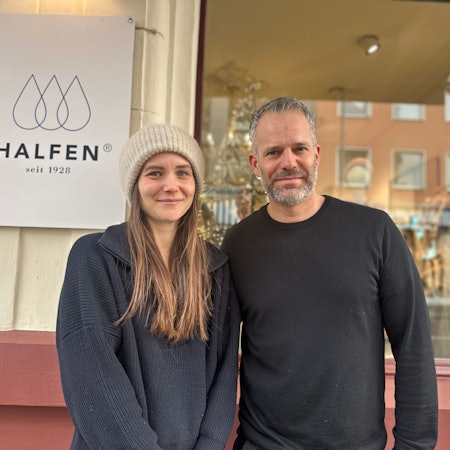 Eine Frau mit langem Haar und Wollmütze steht neben einem Mann mit grauem Haar und Bart.