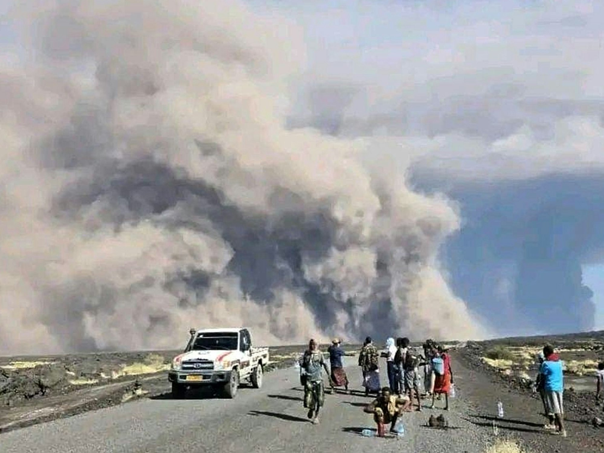 Auf diesem vom Kommunikationsbüro der Afar-Regierung via AP veröffentlichten Foto sehen Menschen die Aschewolken des ersten Ausbruchs des Vulkans Hayli Gubbi in der äthiopischen Region Afar.