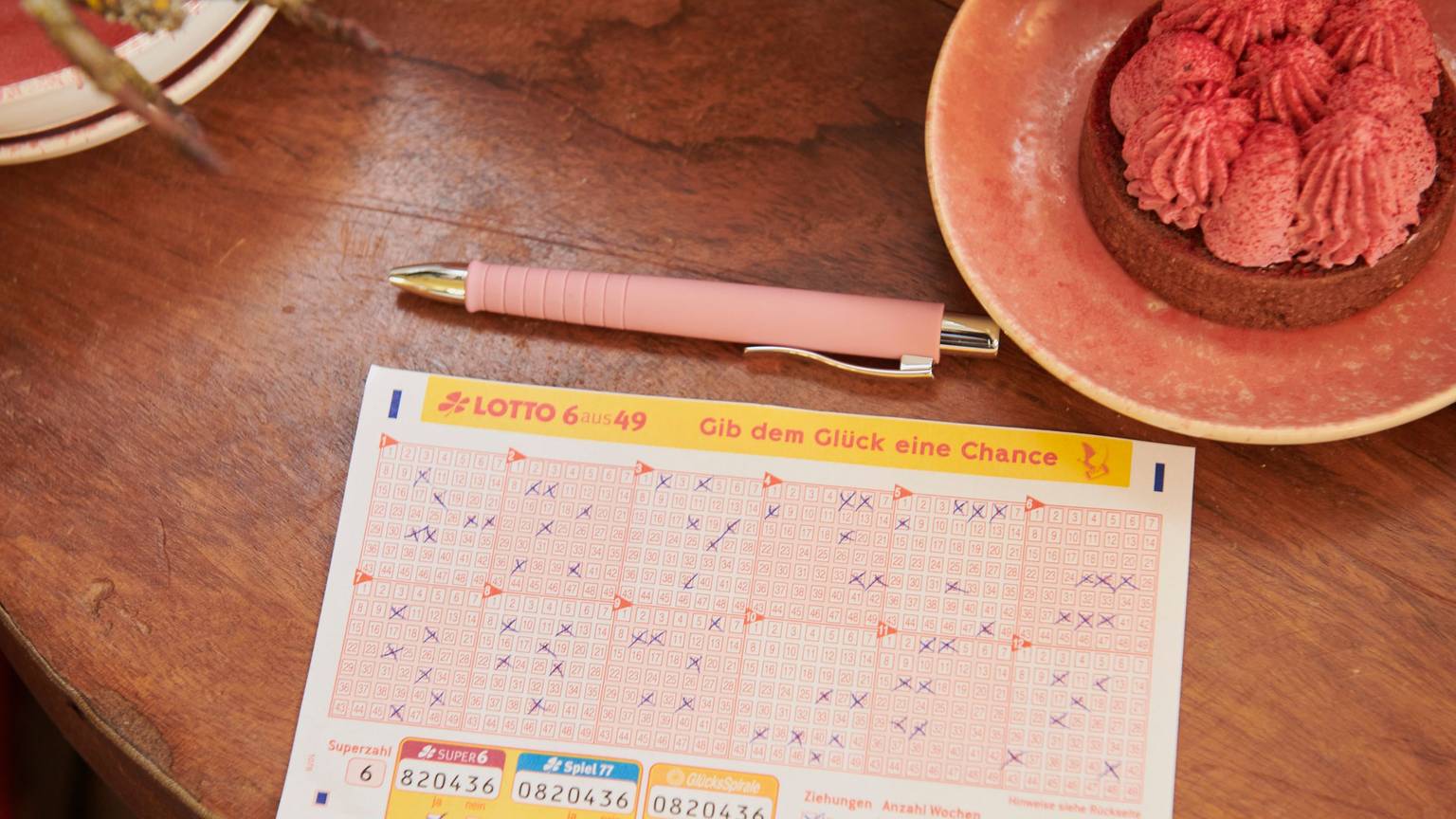 Ein Tippschein für Lotto 6aus49 liegt auf einem Holztisch.
