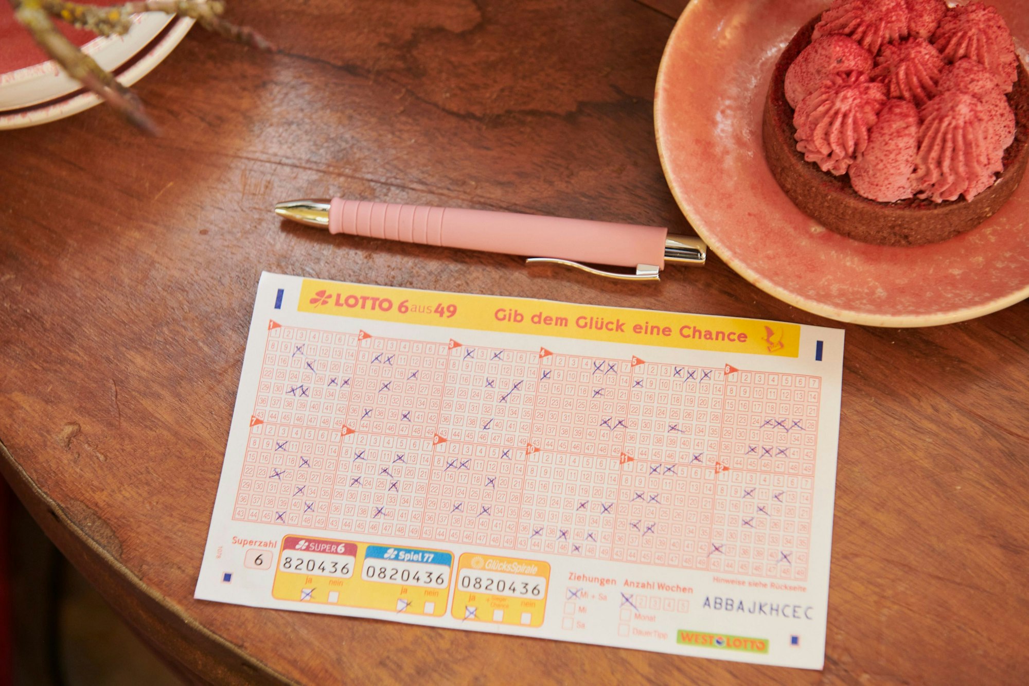 Ein Tippschein für Lotto 6aus49 liegt auf einem Holztisch.