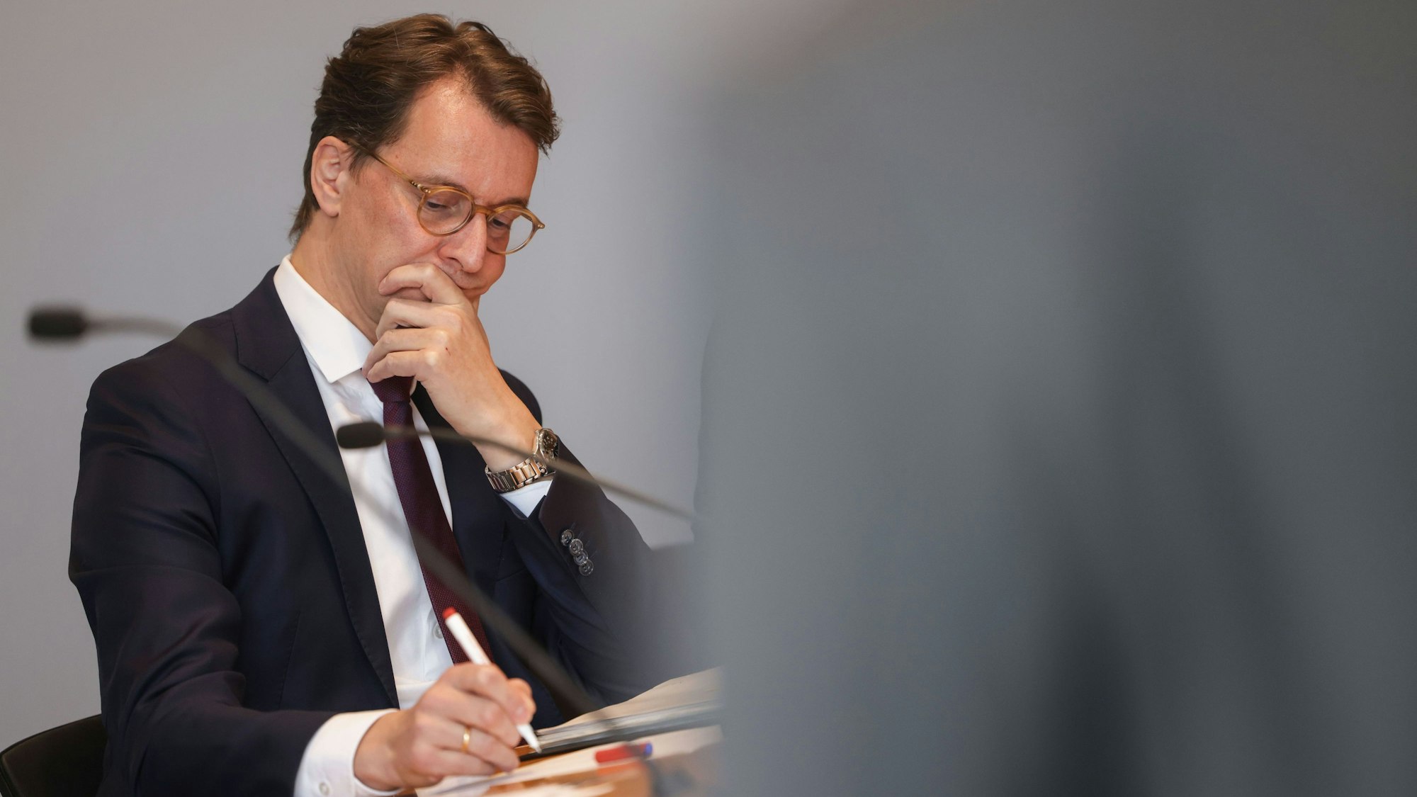 Hendrik Wüst (CDU), Ministerpräsident von Nordrhein-Westfalen, macht sich auf einer Presskonferenz im Landtag Notizen.