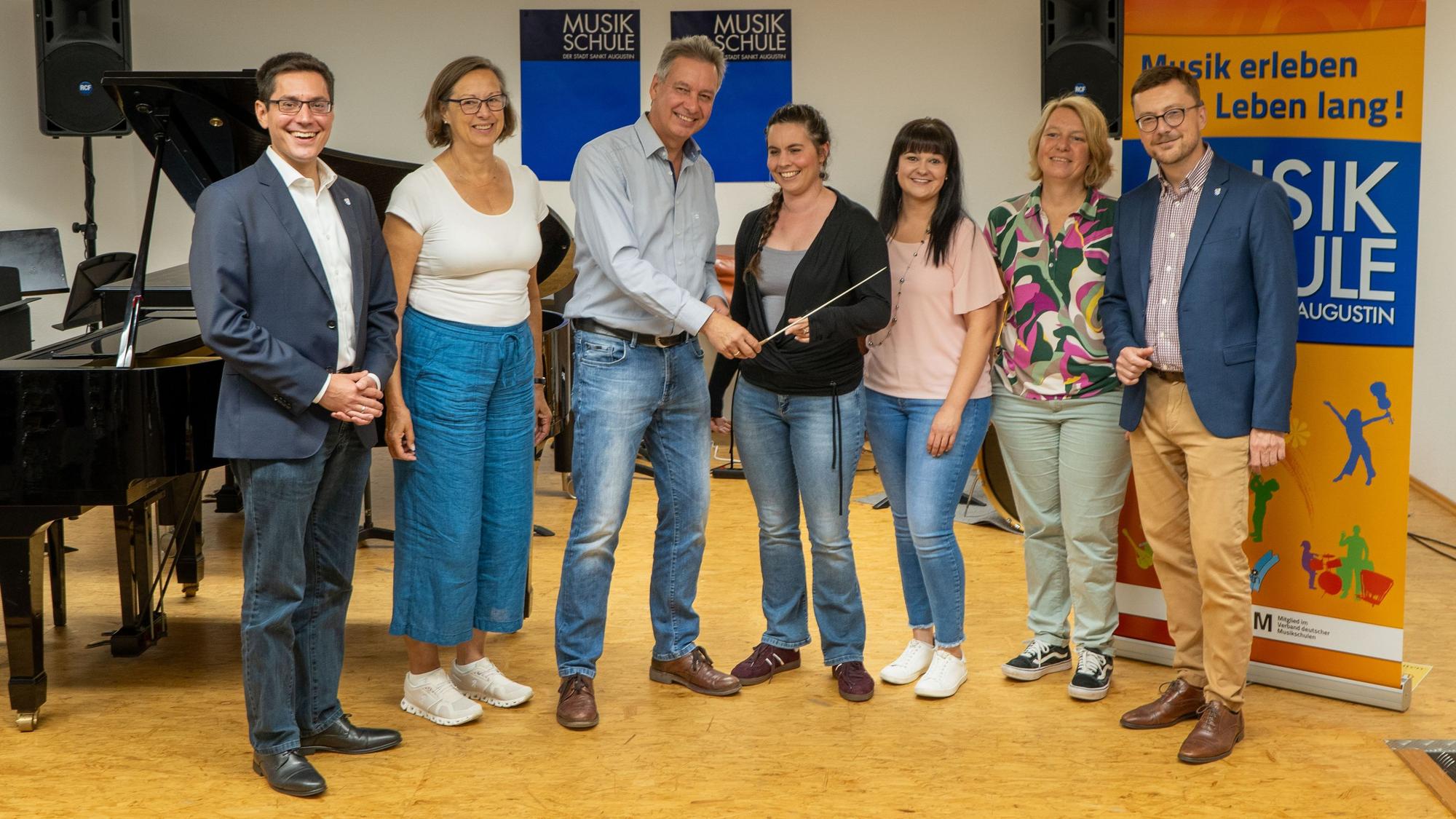 Im Beisein von Bürgermeister Dr. Max Leitterstorf, Martina Kölle, Sandra Fey, Stefanie Will und dem Ersten Beigeordneten Dr. Martin Eßer (v.l.) gab Klemens Salz im vorigen Jahr symbolisch den Dirigentenstab an seine Nachfolgerin Laura Oetzel (Mitte) als Leiterin der Musikschule weiter.