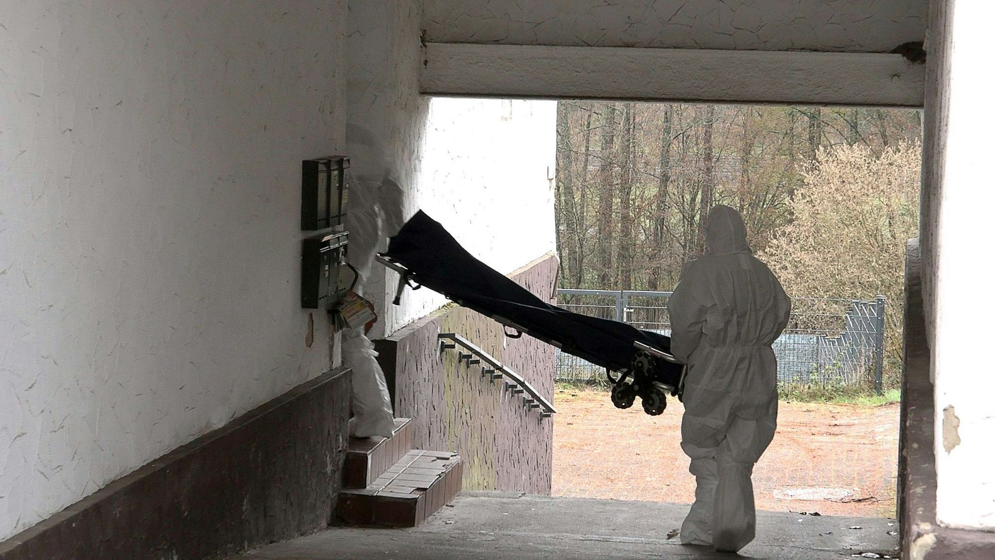 Beamte der Spurensicherung bringen eine Trage in ein Wohnhaus.