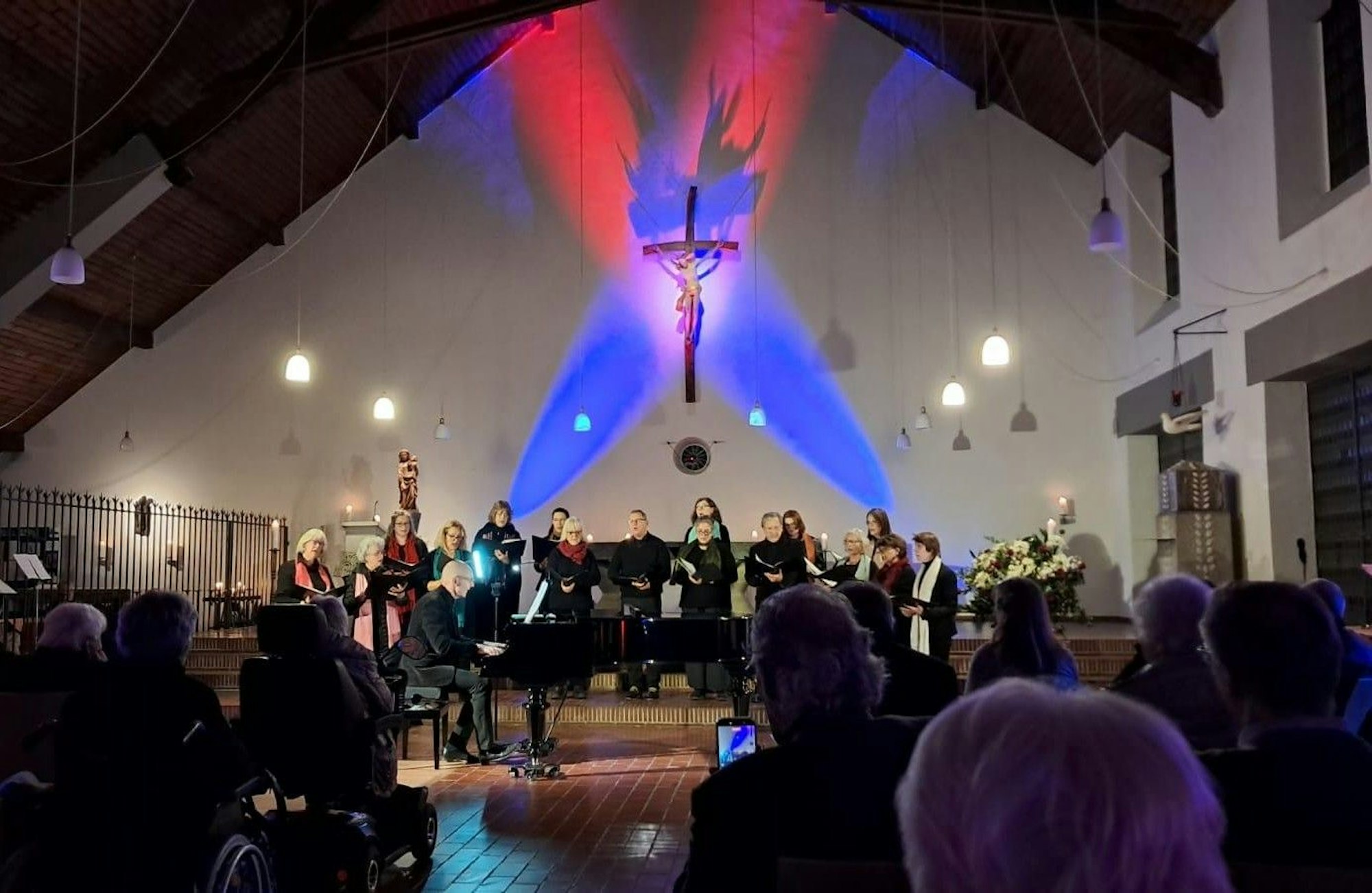 Ein Chor steht in einem Kirchenraum unter einem Kreuz.