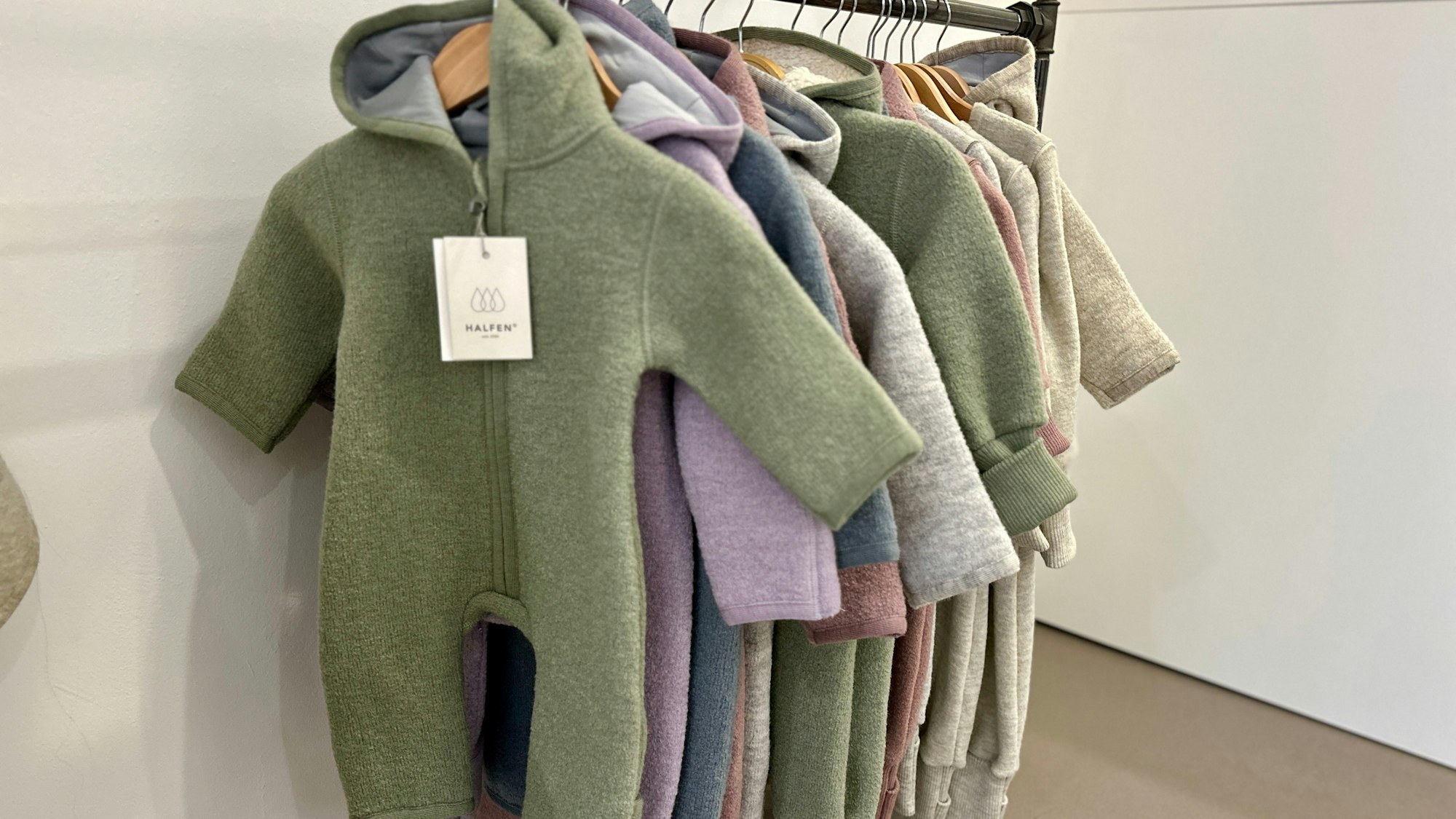 An einem Ständer hängen Woll-Overalls in verschiedenen Farben.