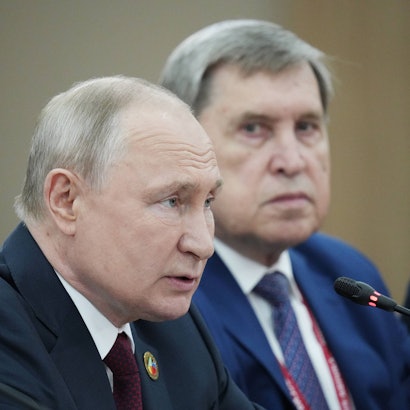 Kremlchef Wladimir Putin spricht in ein Mikrofon. Im Hintergrund ist sein hochrangiger Berater Juri Uschakow zu sehen. (Archivbild)