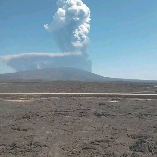 Massive Rauchsäule eines äthiopischen Vulkans über weitläufiger Lavalandschaft unter blauem Himmel