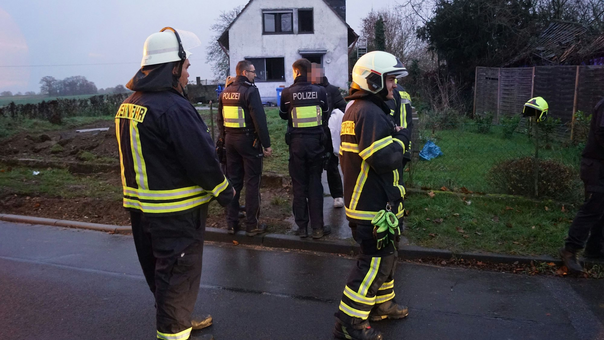 Das Bild zeigt Feuerwehrleute und Polizisten vor dem Einfamilienhaus.