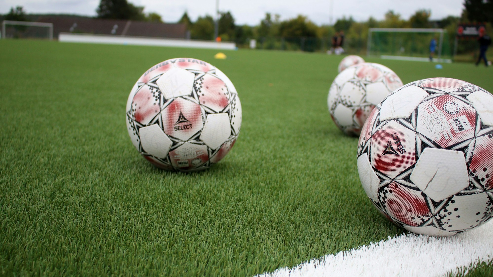 Bälle liegen auf einem Kunstrasenplatz.